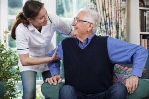 Family members review care documents with an assisted living staff member at a resident’s bedside.